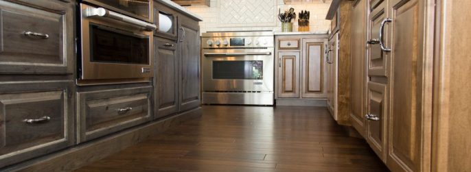 Brown luxury vinyl plank kitchen flooring with a glossy white backsplash.