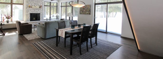 Brown dining room hardwood flooring with a dark wood dining table and a stone fireplace