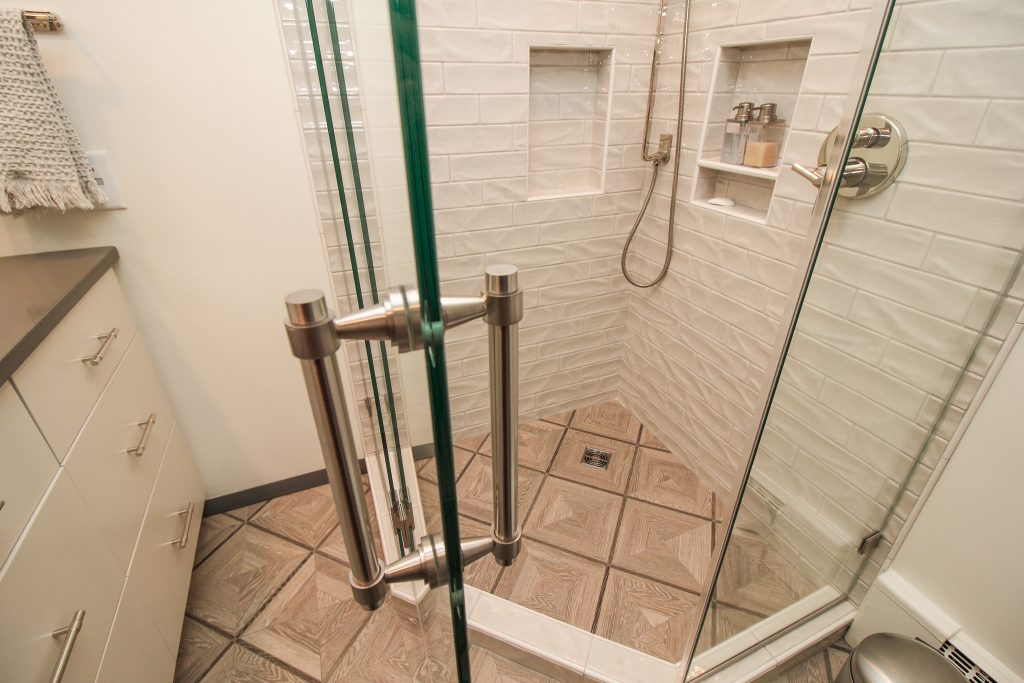 White and glossy brick tiled shower with tan mosaic tile flooring