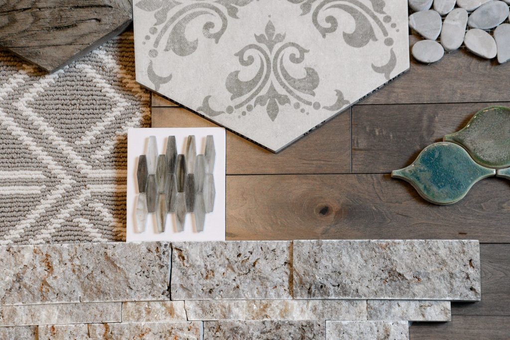 Gray tile, brown hardwood, green tile and gray patterned carpet in a mood board.