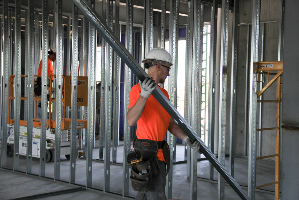 Man installing steel studs on large jobsite.