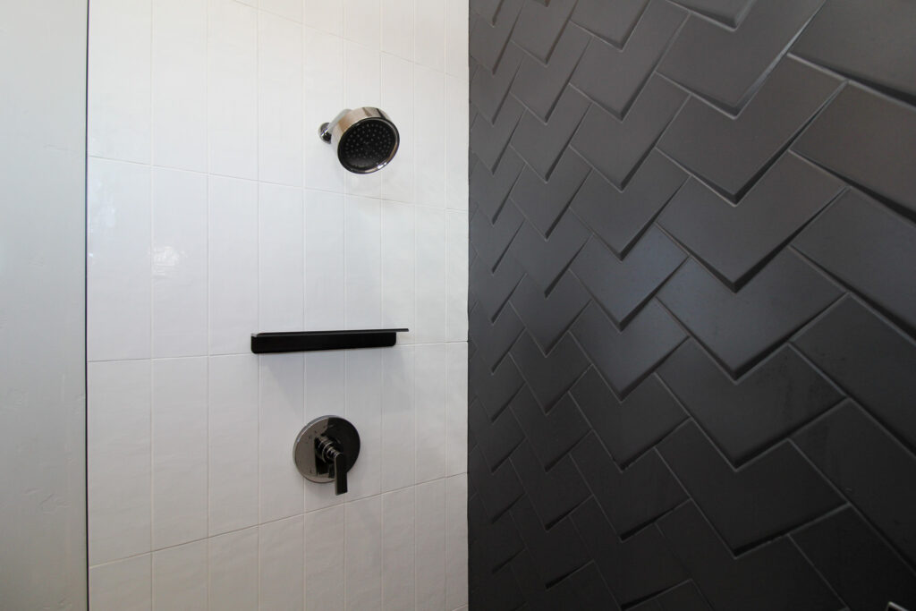 tiled shower with white rectangles and black 3-d diamond tile