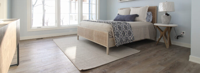 beige hardwood flooring in a light blue bedroom with beige area rug and beadspread