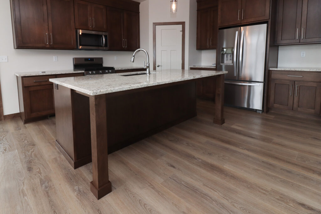 wood look luxury vinyl plank flooring in kitchen with dark cabinets and white counters